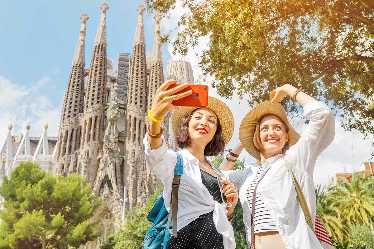 Due turiste davnti alla Sagrada Familia di Barcellona 374 milioni per terminare la Sagrada Familia. Ma i lavori ripartono nel 2024
